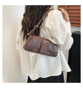 Detail of vintage brown crocodile embossed baguette bag with golden metal buckle
