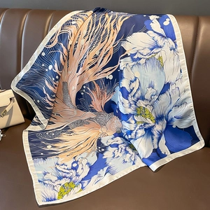 Detail of satin silk scarf with koi fish and peony print draped on a leather couch