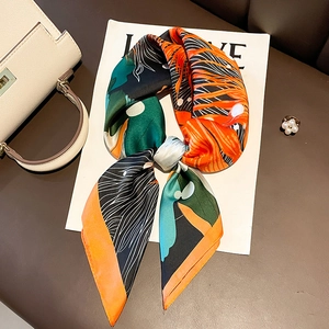 Elegant silk-like square scarf with vibrant abstract print on a premium leather bag