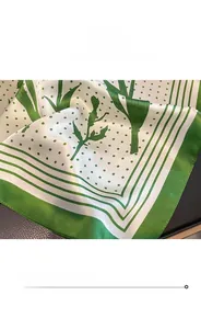 Detail showing the fine stitching edge and silky green botanical pattern on silk scarf