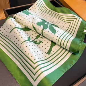 Detail of green and white silk scarf with polka dots and floral pattern in a black box