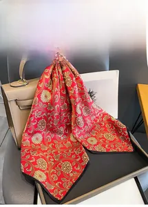Detail of red silk scarf with gold floral pattern draped on a designer handbag