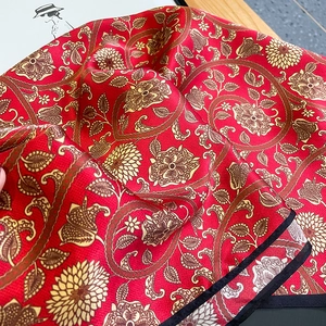 Macro shot of red silk scarf with golden paisley floral print and satin texture