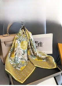 Close-up of silk floral scarf with yellow chrysanthemum pattern on a designer handbag