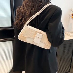 Creamy white baguette bag with crocodile texture and metal buckle on black blazer
