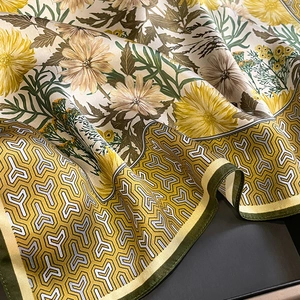 Detailed close-up of a silk scarf featuring yellow daisies and geometric patterns