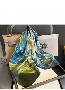 Nahaufnahme eines Seidenquadrattuchs mit Ölgemäldedruck an einer Ledertasche