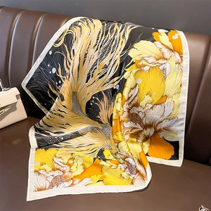 Elegant yellow and white silk-feel floral square scarf draped on a leather chair