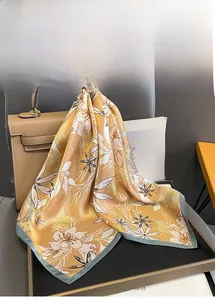 Détail du foulard en soie avec imprimé de lys blanc et bords roulés gris-bleu contrastés
