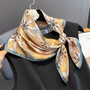Foulard élégant en soie à fleurs jaune gingembre et bleu, noué sur un haut noir chic