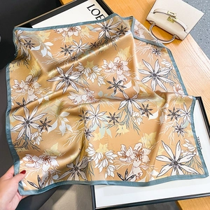 Carré en soie doré élégant avec imprimé fleuri et bordure bleue sur table en bois