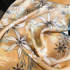 Détail d'un foulard en soie montrant une texture lisse avec imprimé fleuri et bord roulé