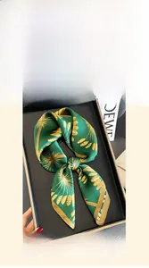 Detailed close-up of a 70x70cm mulberry silk scarf with gold palm leaf patterns in a gift box