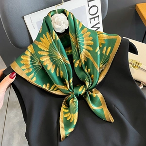 Elegant green silk scarf with golden feather prints, styled on black sleeveless outfit