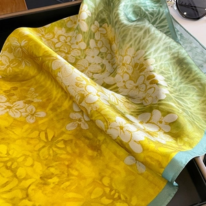 Close-up of yellow-green gradient silk scarf with floral print and hand-rolled edges