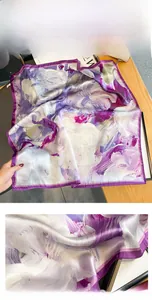 Detail showing the intricate floral print and refined hand-rolled edges of the silk scarf