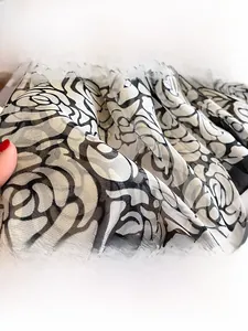 Detail shot of lightweight translucent scarf fabric with black and white rose pattern