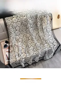 Close-up of black and white camellia print silk scarf with fine rolled edges on a sofa