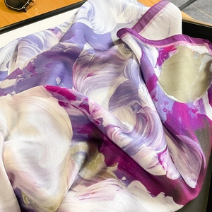 Detailed view of floral silk scarf with vibrant purple and rose prints in a display box