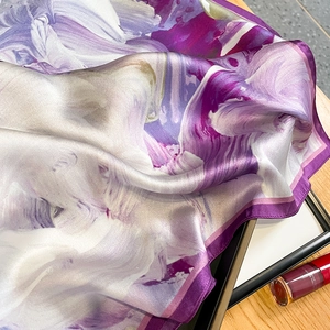 Close-up of premium purple silk scarf showing abstract floral print and hemmed edges