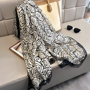 Elegant black and white camellia floral print scarf draped on a leather beige handbag