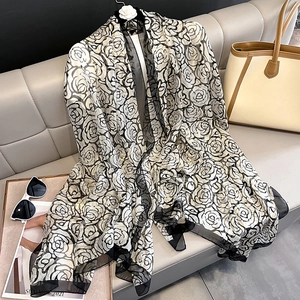 Detail of elegant black and white floral silk scarf draped with chic fashion accessories