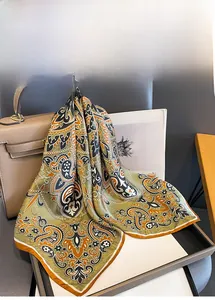 Detail of paisley silk scarf tied to a brown leather handbag for elegant accessory styling