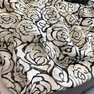 Detailed view of lightweight black and white camellia printed chiffon fabric texture