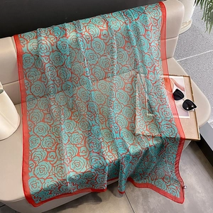 Floral silk shawl with red borders and blue rose pattern on a soft leather sofa