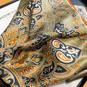 Close-up of silk square scarf featuring olive green paisley and bohemian patterns