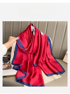 Detail of red floral silk scarf with blue borders held in a luxury home setting