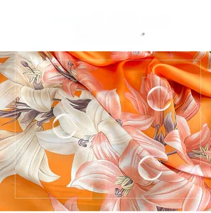 Close-up of orange lily pattern silk scarf showing smooth texture and light sheen