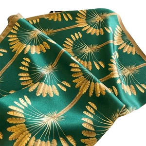 Elegant emerald green silk scarf with golden palm leaf patterns in a folded display