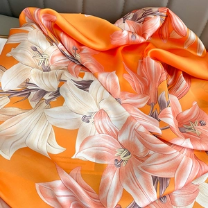 Detailed macro view of orange lily floral print and silky satin texture on summer shawl