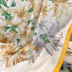 Detail of silk scarf with yellow lily floral print and smooth fabric texture