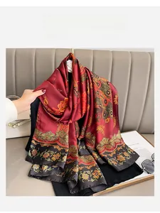 Detailed view of dark red silk scarf with floral and peacock patterns and black border