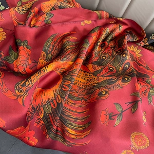 Vintage red silk shawl with golden phoenix and peony floral prints on a gray sofa