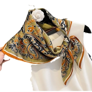 Elegant mulberry silk scarf with paisley pattern tied on neck with flower brooch accessory