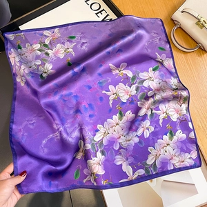Premium silk scarf with purple magnolia print and satin finish on a wooden background