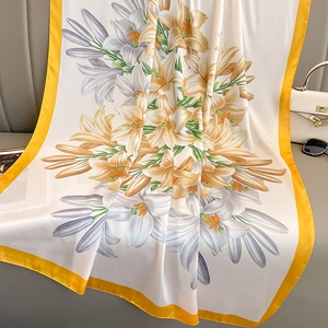 Vintage floral silk scarf with lily prints and yellow borders on a stylish sofa