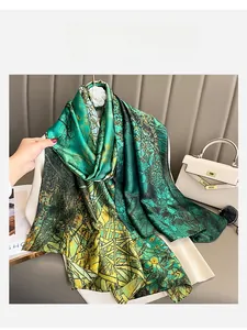 Detail of elegant satin scarf with green and gold floral patterns styled with a white handbag