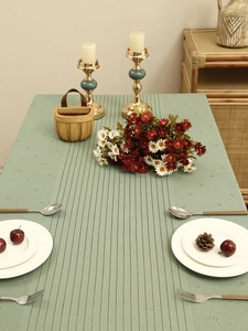 Detail of sage green lace tablecloth with vertical stripe texture and hollow geometric patterns