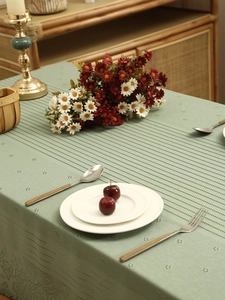Close-up of sage green lace tablecloth with floral hollow patterns and soft linen texture