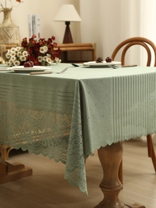 Detail of sage green lace tablecloth with geometric embroidery and hollowed floral edges