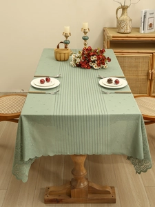 Detail of light green lace tablecloth showing striped texture and floral hollow edges