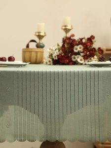 Detail of sage green lace tablecloth featuring vertical hollow stripes and scalloped edges
