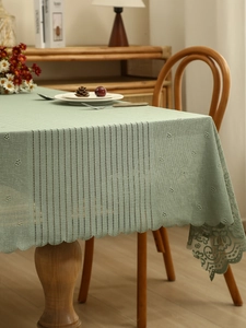 Detail of light green hollow lace tablecloth with crochet stripes and scalloped edges