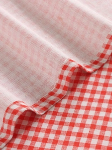 Macro detail of red and white gingham linen curtain fabric with clean hemmed edges