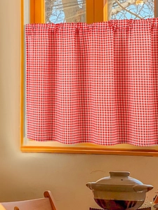 Detail of red and white gingham cafe curtain with rod pocket for kitchen or shelf decoration