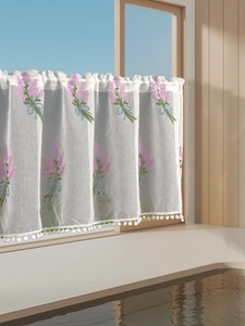 Detail of white semi-sheer tier curtain with purple flower embroidery and pom-pom trim
